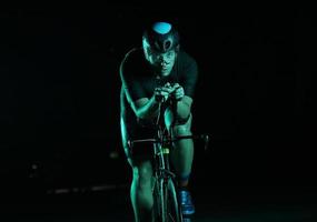 athlète de triathlon faisant du vélo rapidement la nuit photo