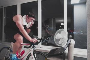 homme faisant du vélo sur l'entraîneur de la machine il s'exerce à la maison la nuit en jouant au jeu de course de vélo en ligne photo