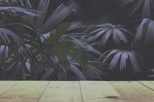 table en bois et feuilles de palmier tropical luxuriant. photo