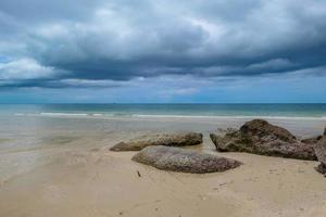 rochers en bord de mer sur la belle plage le matin avec un nuage de pluie. photo