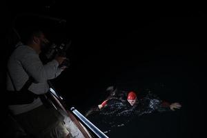 vidéaste prenant une photo d'action d'un athlète de natation de triathlon la nuit