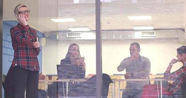 femme d'affaires regardant à travers une fenêtre et utilisant un téléphone portable lors d'une réunion d'affaires photo