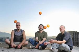 trois hommes jouant en plein air avec des fruits orange photo