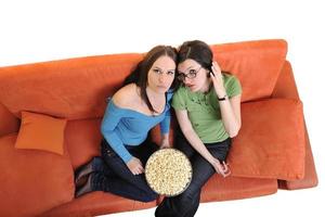 Amies manger du pop-corn et regarder la télévision à la maison photo