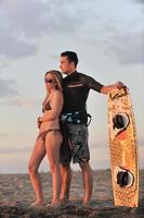 couple de surf posant sur la plage au coucher du soleil photo