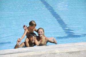 une jeune famille heureuse s'amuse à la piscine photo