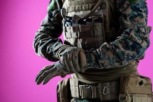 gros plan des mains du soldat mettant des gants de protection sur fond rose