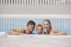 une jeune famille heureuse s'amuse à la piscine photo