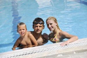 une jeune famille heureuse s'amuse à la piscine photo