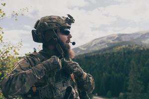 notion de guerre. un soldat barbu en uniforme des forces spéciales combattant un ennemi dans une zone forestière. mise au point sélective photo