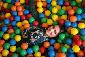 jeune maman jouant avec des enfants dans la piscine avec des boules colorées photo