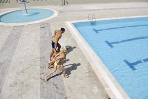 une jeune famille heureuse s'amuse à la piscine photo