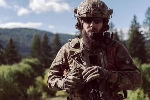 notion de guerre. un soldat barbu en uniforme des forces spéciales combattant un ennemi dans une zone forestière. mise au point sélective photo