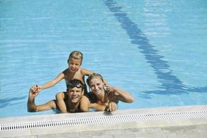 une jeune famille heureuse s'amuse à la piscine photo