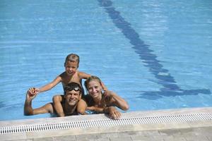 une jeune famille heureuse s'amuse à la piscine photo