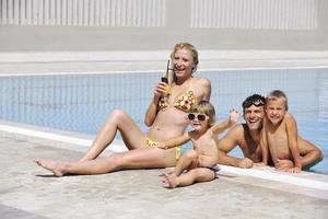 une jeune famille heureuse s'amuse à la piscine photo