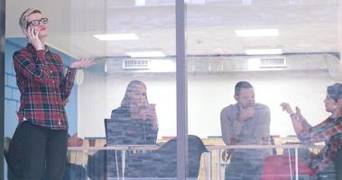 femme d'affaires regardant à travers une fenêtre et utilisant un téléphone portable lors d'une réunion d'affaires photo