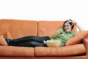 jeune femme mange du pop-corn sur un canapé orange photo