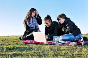 groupe d'adolescents travaillant sur un ordinateur portable en plein air photo