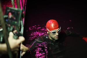 vidéaste prenant une photo d'action d'un athlète de natation de triathlon la nuit