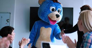 patron habillé en ours s'amusant avec des gens d'affaires dans un bureau branché photo