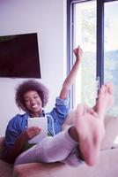 femme afro-américaine à la maison dans une chaise avec tablette et casque photo