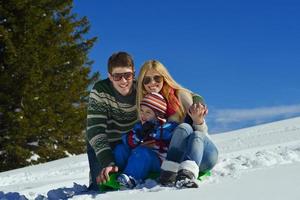 famille s'amusant sur la neige fraîche en hiver photo