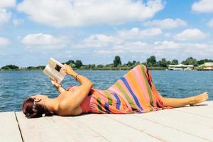 femme relaxante sur une jetée et lisant un livre. photo