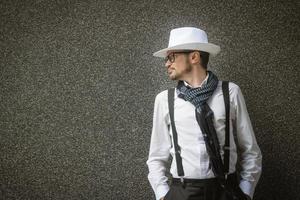 homme à la mode avec un chapeau contre le mur gris. photo