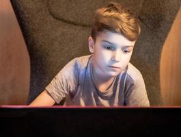 petit garçon utilisant un ordinateur et jouant à des jeux en ligne à la maison. photo