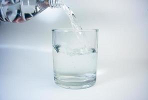 verser de l'eau dans un verre sur un fond blanc photo