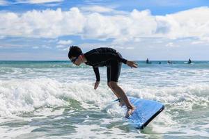 jeune garçon, nouvel étudiant en surf, perd l'équilibre de son corps et tombe d'une planche de surf dans l'eau pendant les cours. photo