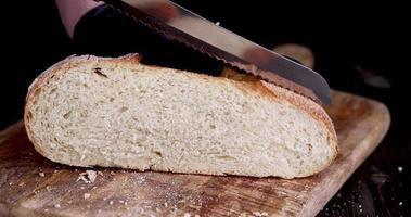 couper en morceaux du pain de seigle frais pendant la cuisson photo