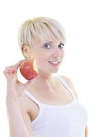 heureuse jeune femme mange une pomme verte isolée sur blanc photo