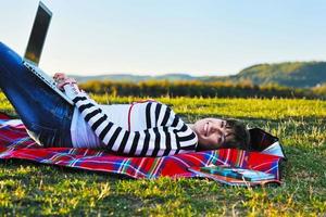 jeune adolescente travaille sur un ordinateur portable en plein air photo