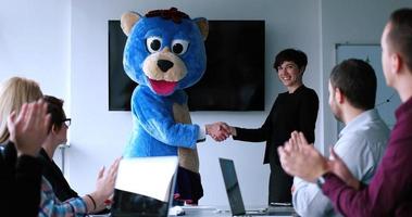 patron habillé en ours s'amusant avec des gens d'affaires dans un bureau branché photo