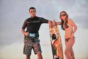 couple de surf posant sur la plage au coucher du soleil photo