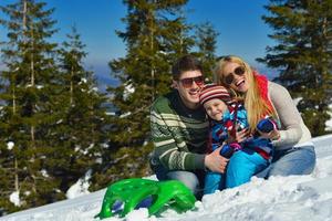 famille s'amusant sur la neige fraîche en hiver photo