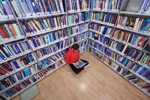 les élèves utilisent un cahier, un ordinateur portable et une bibliothèque scolaire photo