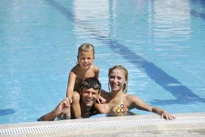 une jeune famille heureuse s'amuse à la piscine photo