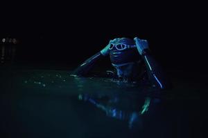 authentique nageur triathlète ayant une pause pendant un entraînement intensif sur la lumière du gel néon de nuit photo