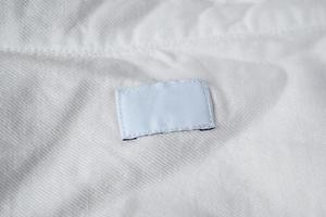 étiquette blanche de vêtements de soin de blanchisserie vierge sur une chemise en coton photo