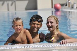 une jeune famille heureuse s'amuse à la piscine photo