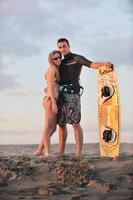 couple de surf posant sur la plage au coucher du soleil photo