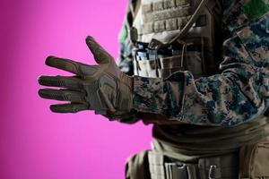 gros plan des mains du soldat mettant des gants de protection sur fond rose photo