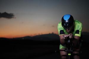 athlète de triathlon faisant du vélo rapidement la nuit photo