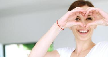 Signe de coeur fait main par jeune femme, maison photo