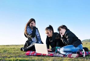 groupe d'adolescents travaillant sur un ordinateur portable en plein air photo