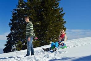 famille s'amusant sur la neige fraîche en hiver photo