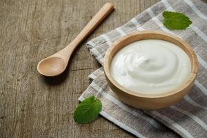 Yaourt grec dans un bol en bois avec des cuillères sur fond de bois photo